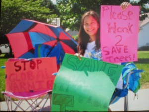 Freshman Devon McVey holds up signs to protest against the cutting down of trees. McVey and her neighbors tallied up all the honks she received in protest against cutting down trees and they planned to send the tallies to the mayor.